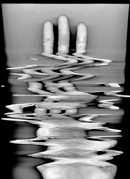Black-and-white scan of a hand, with fingers and palm stretched into horizontal waves.